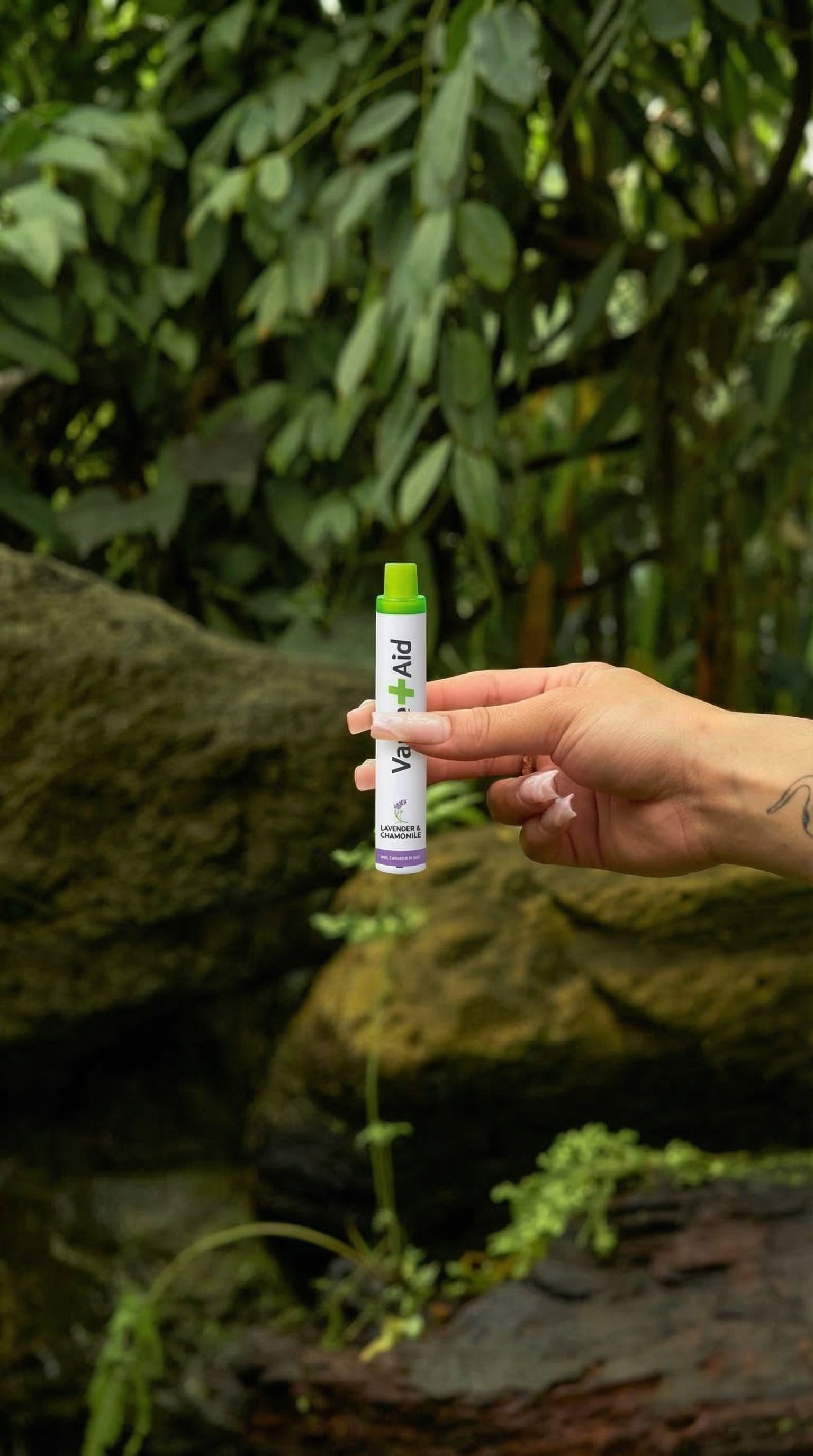Hand holding a Vape+Aid diffuser outdoors against a natural background