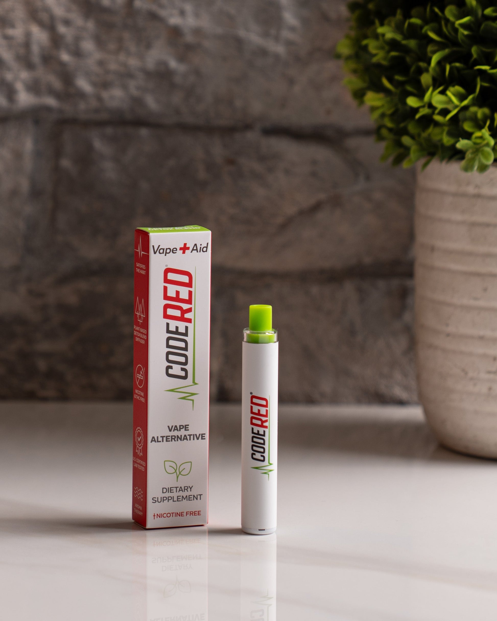 Code Red Vape+Aid and packaging on a surface with a plant in the background