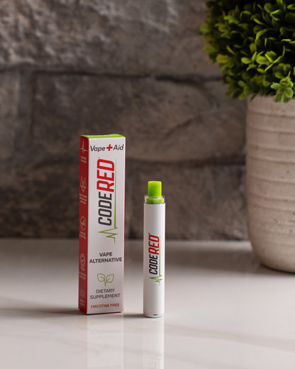 Code Red Vape+Aid and packaging on a surface with a plant in the background