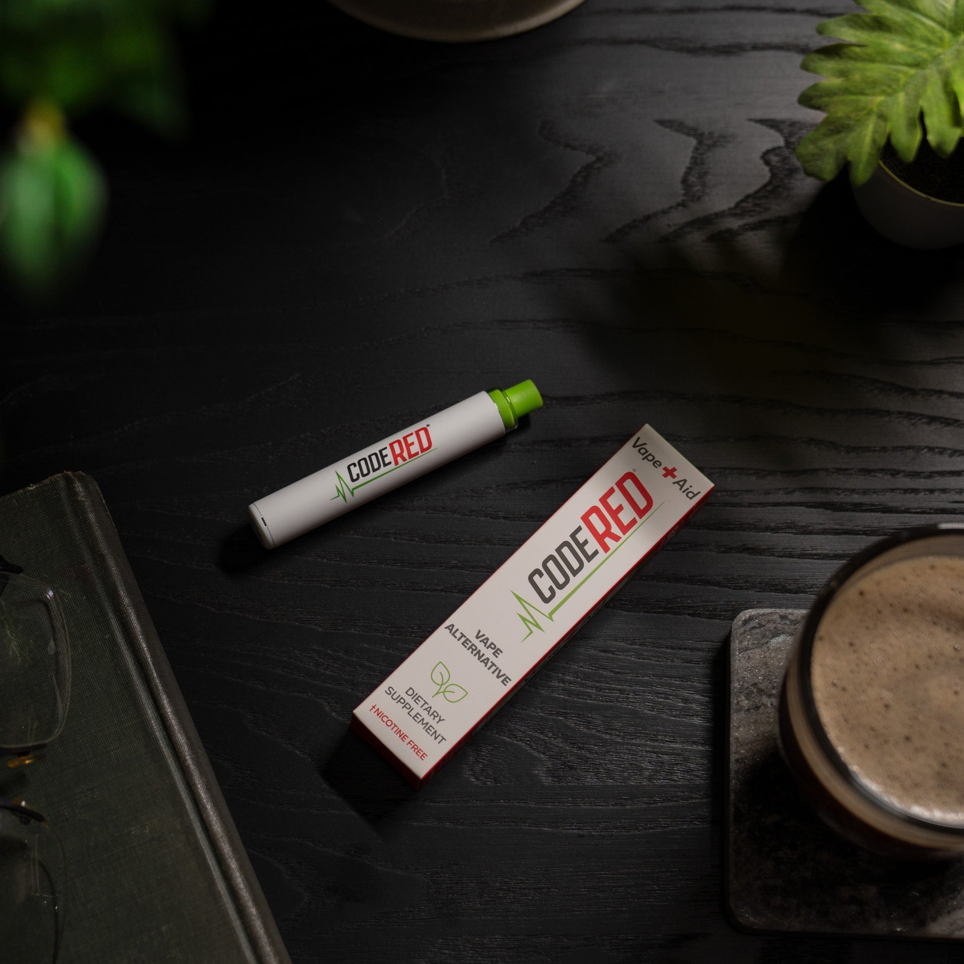 Code Red Vape+Aid and packaging on a dark wooden surface with a cup of coffee